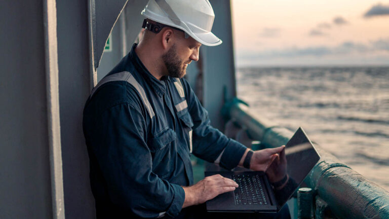 Un marino con un portátil a bordo de un buque.