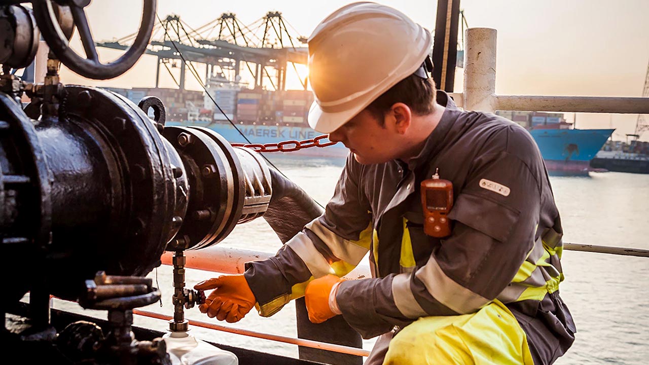 Un operario toma una muestra de combustible durante una operación de bunkering.
